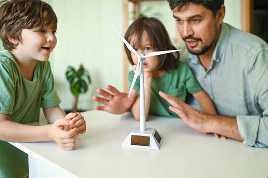 Father and sons examining wind turbine model at home
