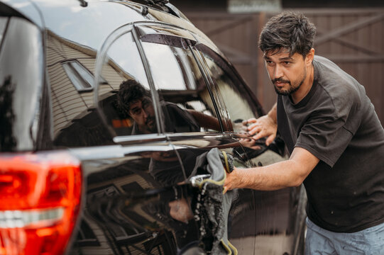 Man cleaning car door with rag
