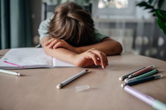 Tired boy resting head on table after doing homework
