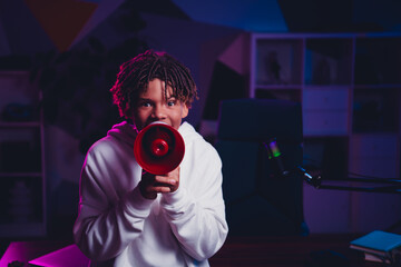 Teenager enthusiastic gamer and vlogger using a megaphone in a colorful room for online streaming and broadcasting