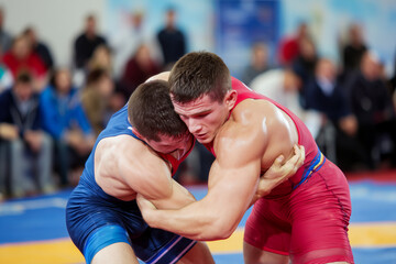 Two Greco-Roman or Freestyle Wrestling athletes during competition. Wrestling match.