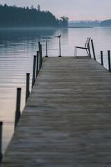 Naklejka premium Quiet dock at dawn with a lone chair and a bird in Finland