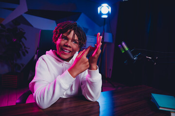 Youthful male vlogger recording in neon light ambience with a microphone and engaging in social media discussions