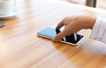 Notification. Closeup of lady taking cell phone off desktop or laying it down on table