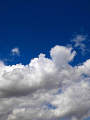 Obraz premium Fluffy white clouds float against a vibrant blue sky on a sunny day