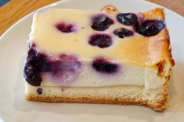 Delicious blueberry cheesecake served on a white plate in a cozy cafe setting during the afternoon