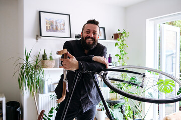 Smiling businessman leaning on bicycle at home
