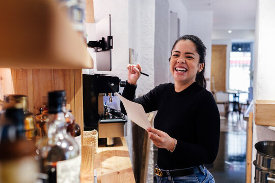 Cheerful restaurant owner standing with document in illuminated kitchen