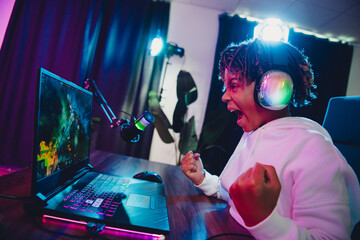 Teenager Young gamer enjoying a victory while blogging or streaming live in a neon-lit gaming setup