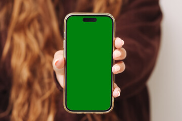 Woman holding smartphone. Green screen on mobile display. Mockup for app or website. Female hand...