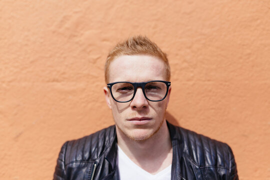 Portrait of strawberry blonde young man wearing black glasses