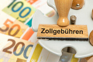 Ein Holzstempel ist beschriftet mit dem Aufdruck Zollgebühren als Symbol für den Zollstreit und...