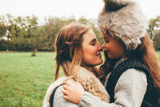 Young woman and her little daughter rubbing their noses in an autumnal park