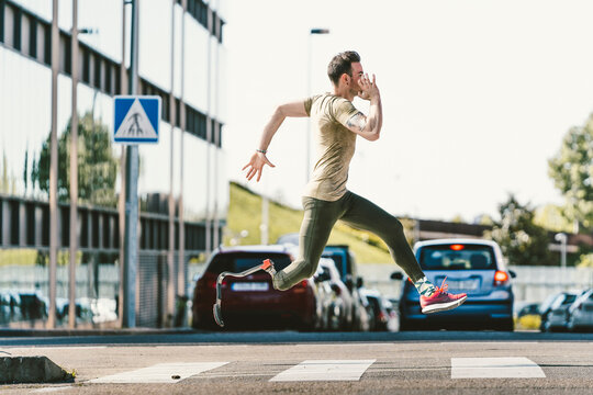 Disabled athlete with leg prosthesis exercising in the city on a zebra crossing