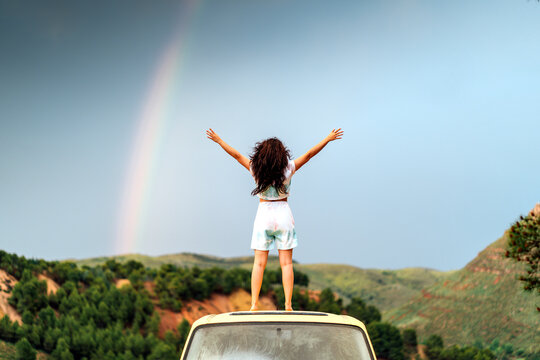 Woman with arms outstretched standing on van