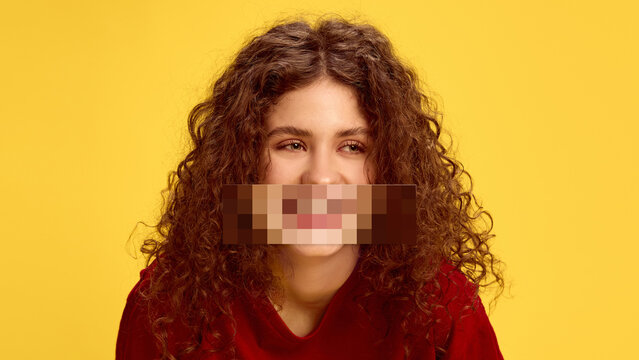 Surreal collage. Portrait of happy curly-haired girl on yellow background with pixelated mouth. Concept of filtered speech, emotional masking, youth expression, and censorship.