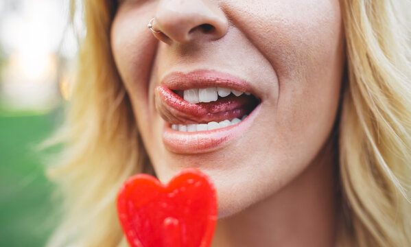 Close-up of young woman licking heart-shaped lollipop