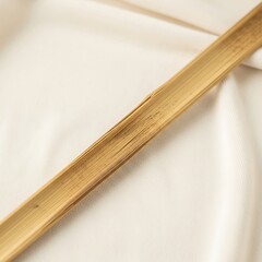 Close-up of a section of bamboo stalk lying diagonally across a white, slightly wrinkled fabric surface.
