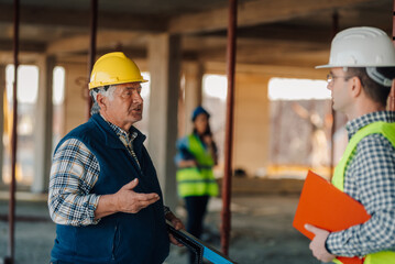 Construction workers discussing on site wearing hard hats and safety vest
