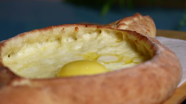 Top view of khachapuri with its signature yellow egg yolk and creamy cheese surrounded by crispy baked dough.
