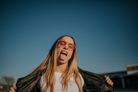 Portrait of young woman outdoors sticking out tongue