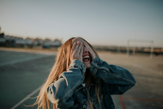 Cheerful young woman covering her eyes outdoors