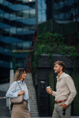Business partners enjoying a coffee break while discussing a project in front of their office building
