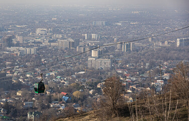 Obraz premium A green cable car travels up Koktobe mountain funicular overlooking Almaty city, Kazakhstan. 