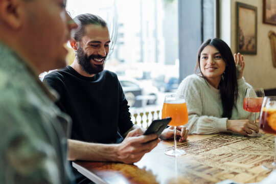 Male and female friends with drinks at table in bar