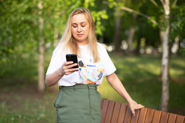Pretty woman taking selfie with mobile phone looking at camera in a park. Blogger recording video...
