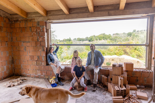 Happy family sitting in window sill with dog at home