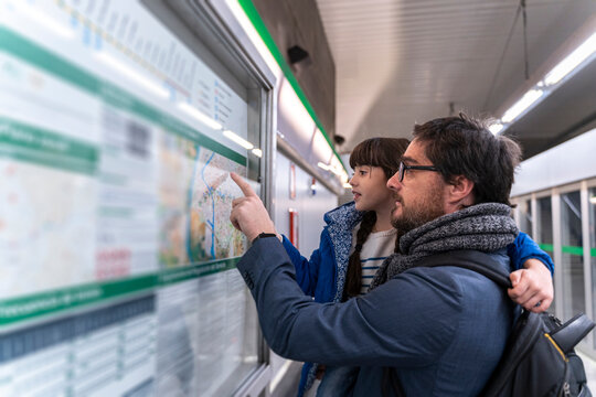 Father and daughter looking on map at metro station