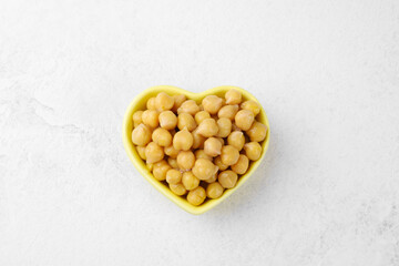 Heart shaped bowl of chickpeas on white background for love food, healthy vegan lifestyle or plantbased nutrition concept