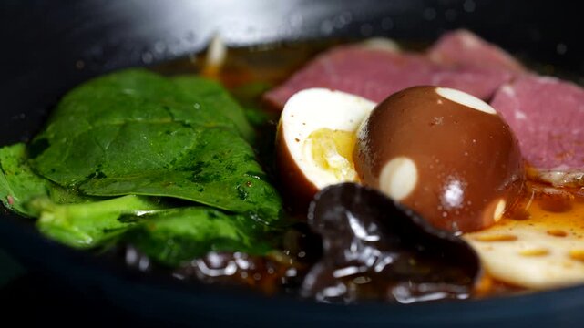 Spinach leaves, soy-marinated egg, mushrooms, and beef slices floating in rich ramen broth.