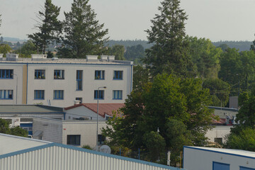 A large building featuring numerous windows is beautifully surrounded by lush green trees, creating...
