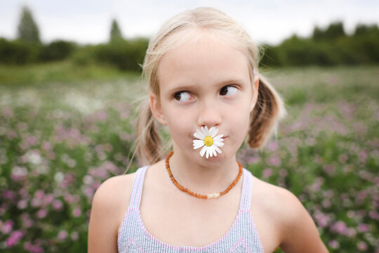 Girl with chamomile flower in her mouth
