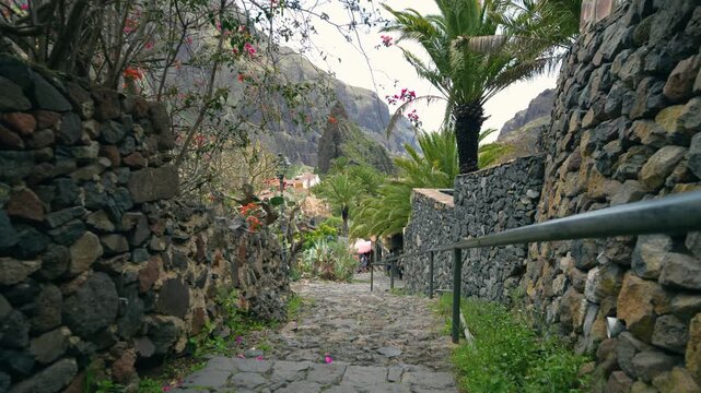Walking down pedestrian street in Masca village with scenic view of iconic ravine and cliffs, Tenerife, Canary Islands, sunny day travel footage