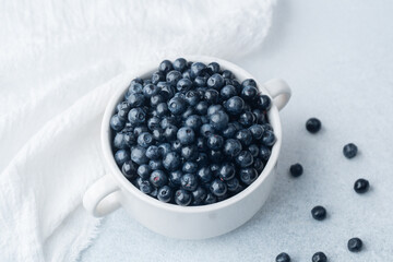 Blueberries in white bowl with soft cloth for comfort, diet or organic eating concept