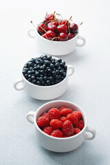 Bowls of raspberries, blueberries and cherries for fruit trio, diet or nutrition concept