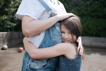 Daughter and mother embracing each other at back yard