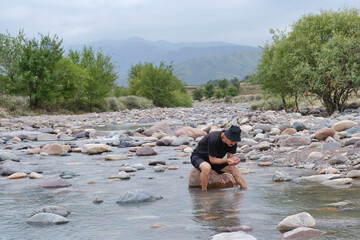Elderly Man Collecting Water from Mountain River
