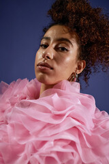 Vertical portrait shot of young adult multiethnic woman gazing into camera, wearing voluminous...