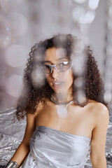 Vertical portrait shot of young adult multiethnic woman with curly hair wearing metallic glasses...