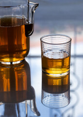 Iced tea in a crystal glass, carafe and lemons on a marble table at golden hour