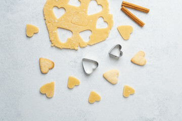 Heart cookies and baking dough on pastel background with cinnamon for romantic, food blog or recipe concept