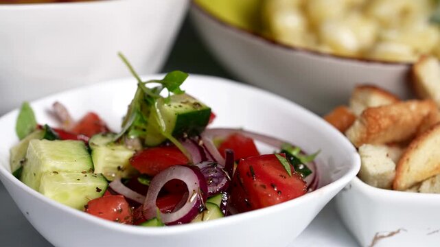 Fresh cucumber, tomato, and red onion salad with herbs served in a white bowl, vibrant and colorful.