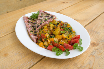 ready to eat - roasted potatoes and aspic with cherry tomatoes and herbs, served on a white plate