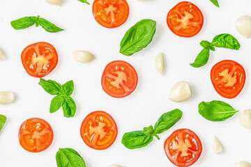 Flat lay of fresh tomato slices, garlic cloves, and basil leaves on white background