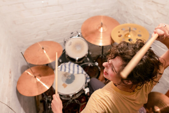 Carefree young woman playing drums in basement