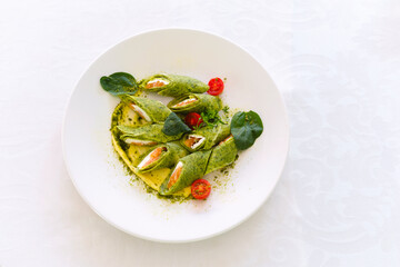 Freshly prepared cannelloni with spinach filling served on a white plate